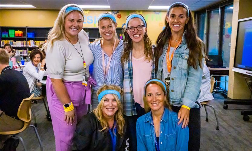 Teachers pose while wearing neon sweatbands